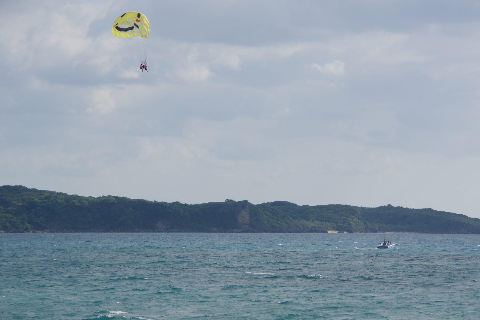海の上をパラセーリングで飛ぶ人と、ロープでけん引するボート