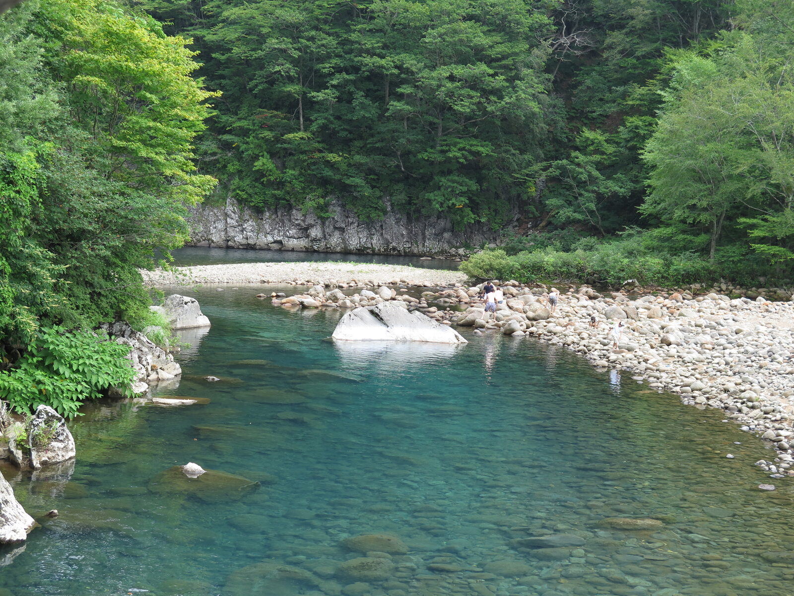 法体の滝下流、河原で水遊びを楽しむ人々とエメラルドグリーンの淵