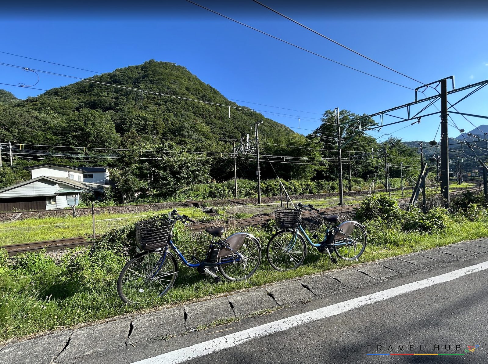 上越線の線路沿いに停めたレンタサイクル2台と山並み