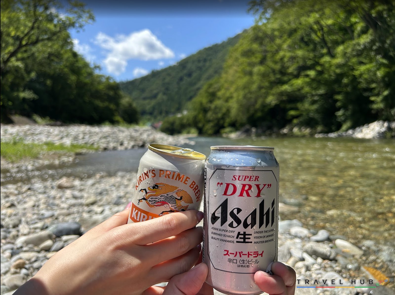 利根川の川辺で缶ビールを掲げて乾杯する手元