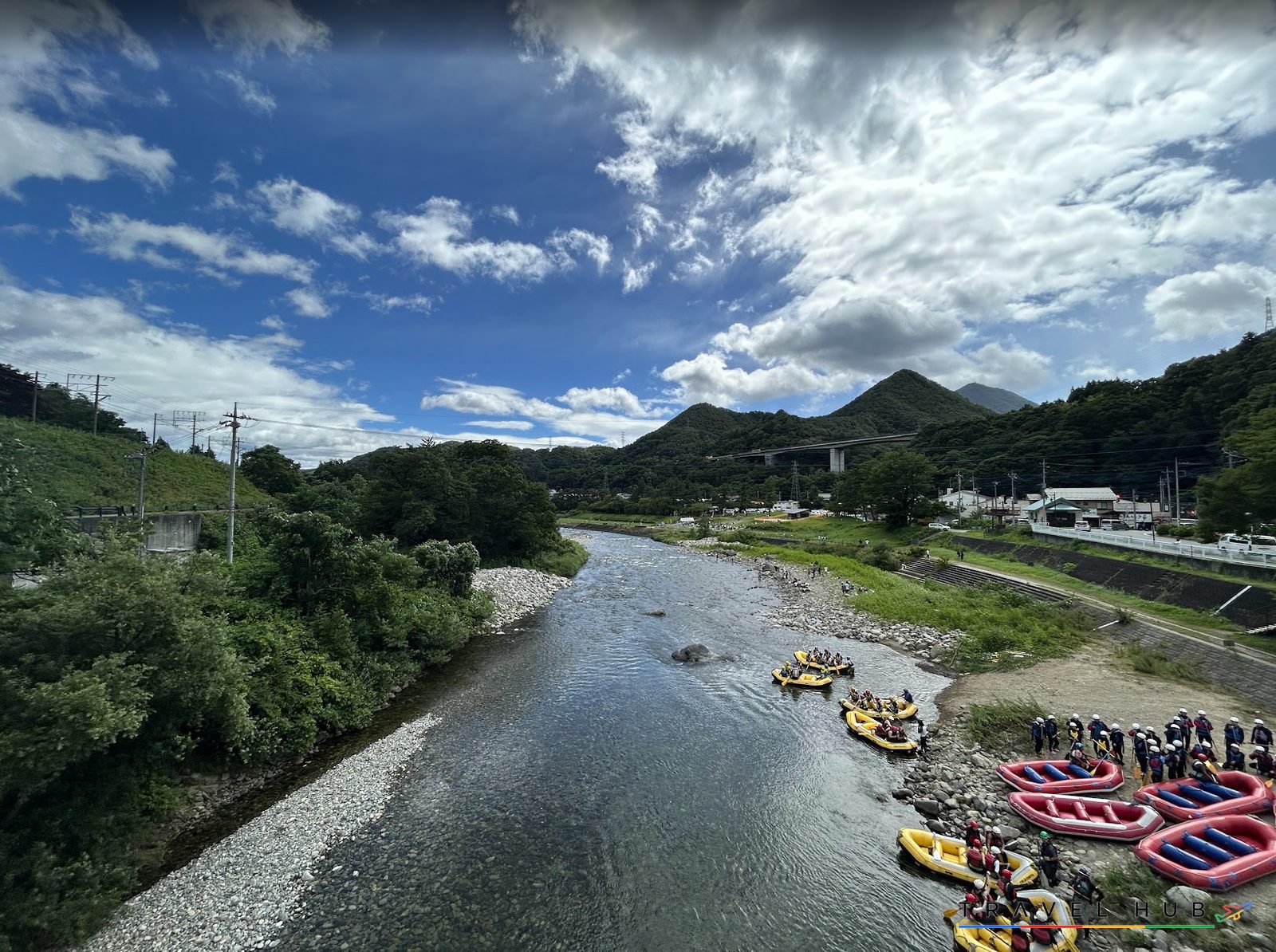 橋の上から見下ろす利根川の川原に並ぶラフティングのボート