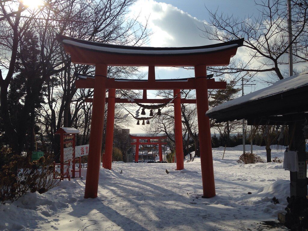 雪に包まれた虻田神社の朱塗りの鳥居、冬の参道