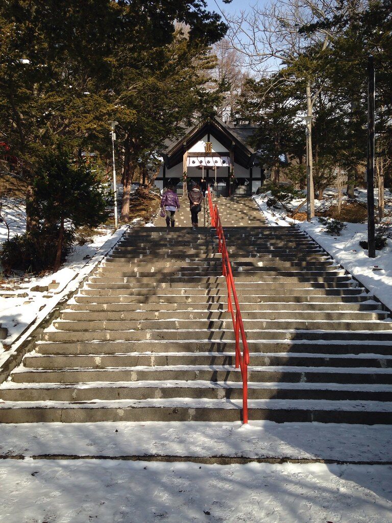 虻田神社の石段を上る参拝者と、石段の先に見える社殿