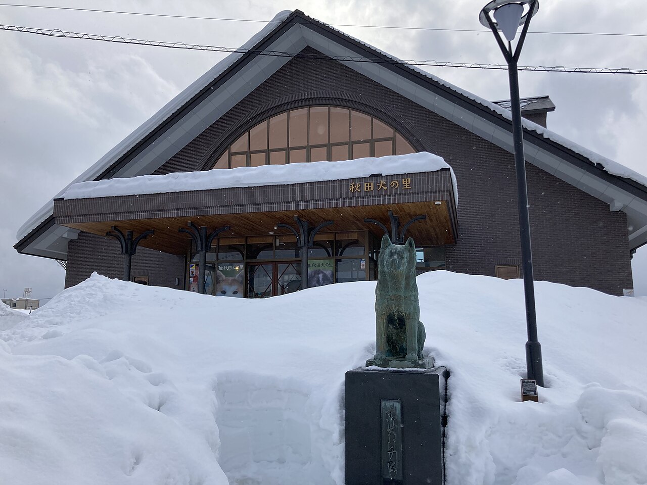 雪に覆われた秋田犬の里の外観と秋田犬の銅像