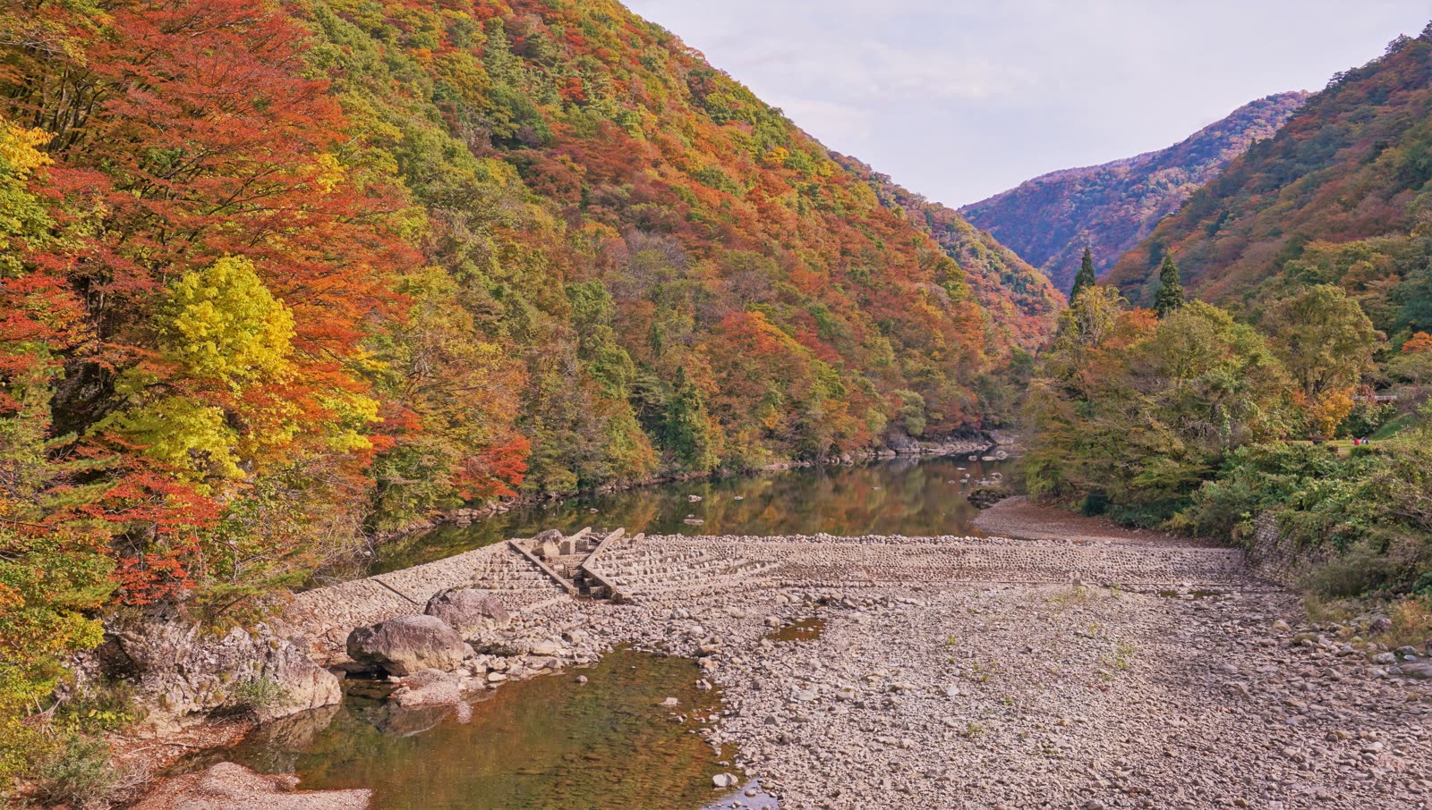 抱返り渓谷の紅葉した山肌と玉川の流れ、河原の風景