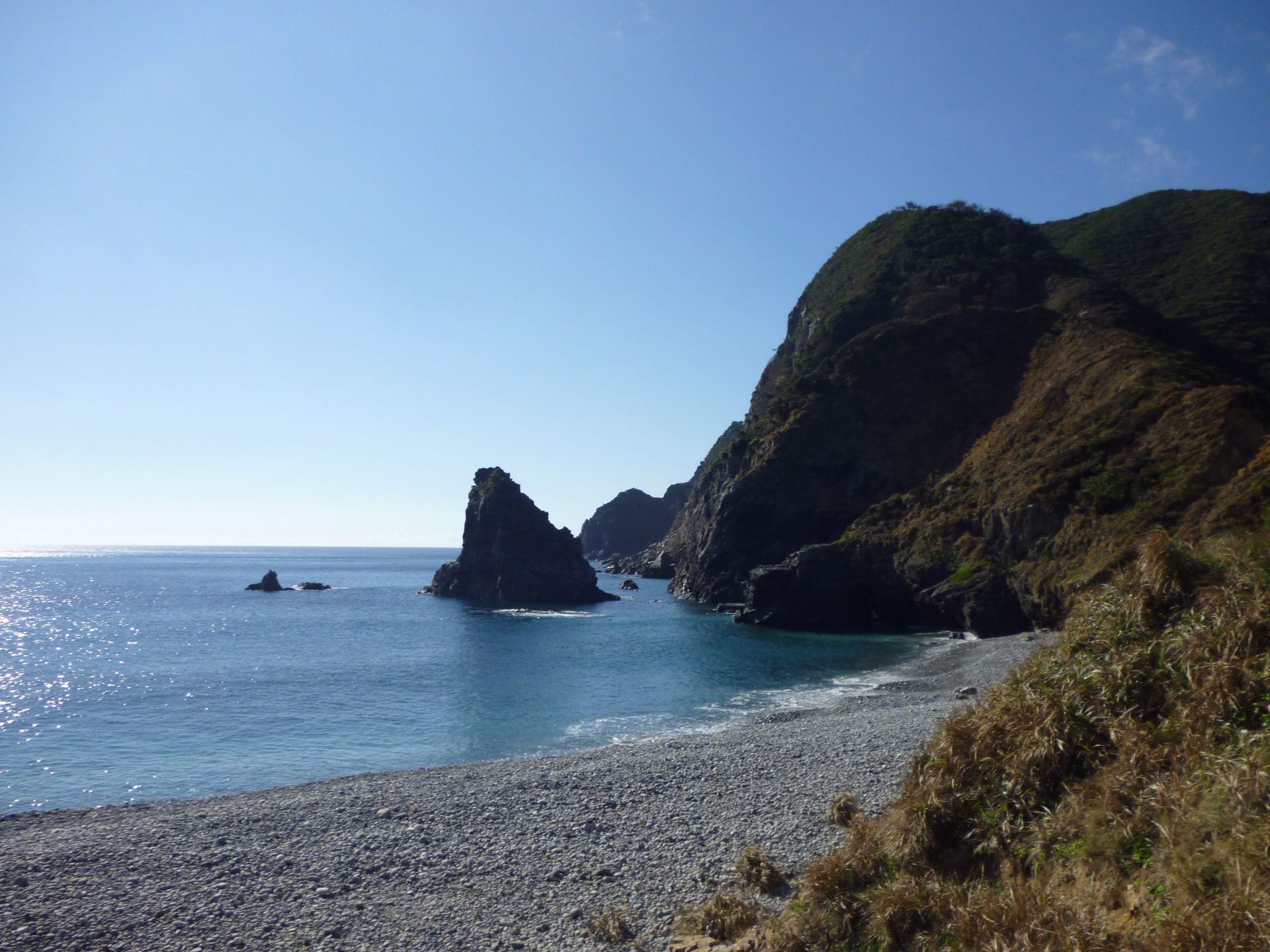 ホノホシ海岸の玉石の浜から望む海上の奇岩と岬