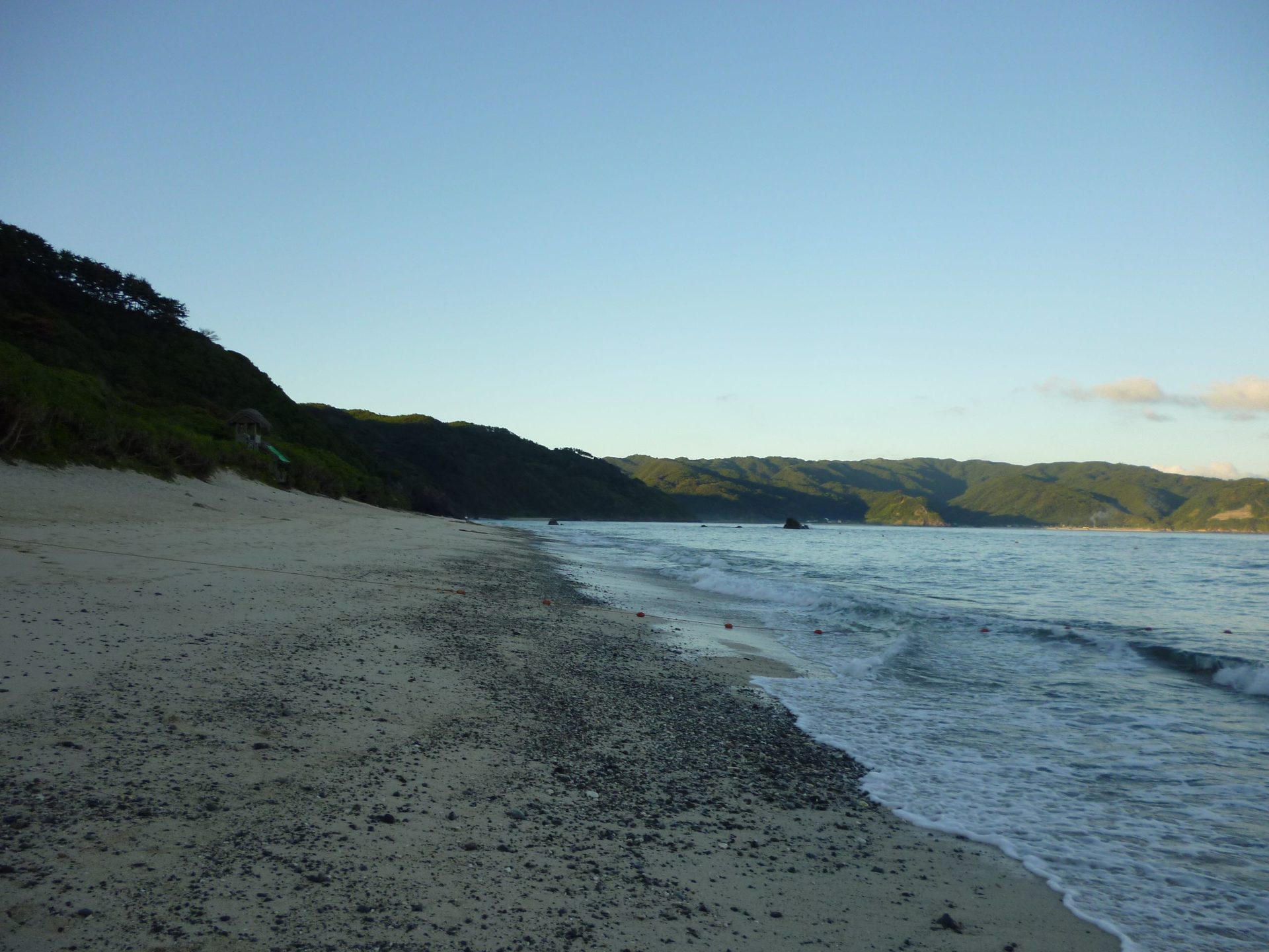 緑の岬に沿って続く大浜の砂浜と波打ち際