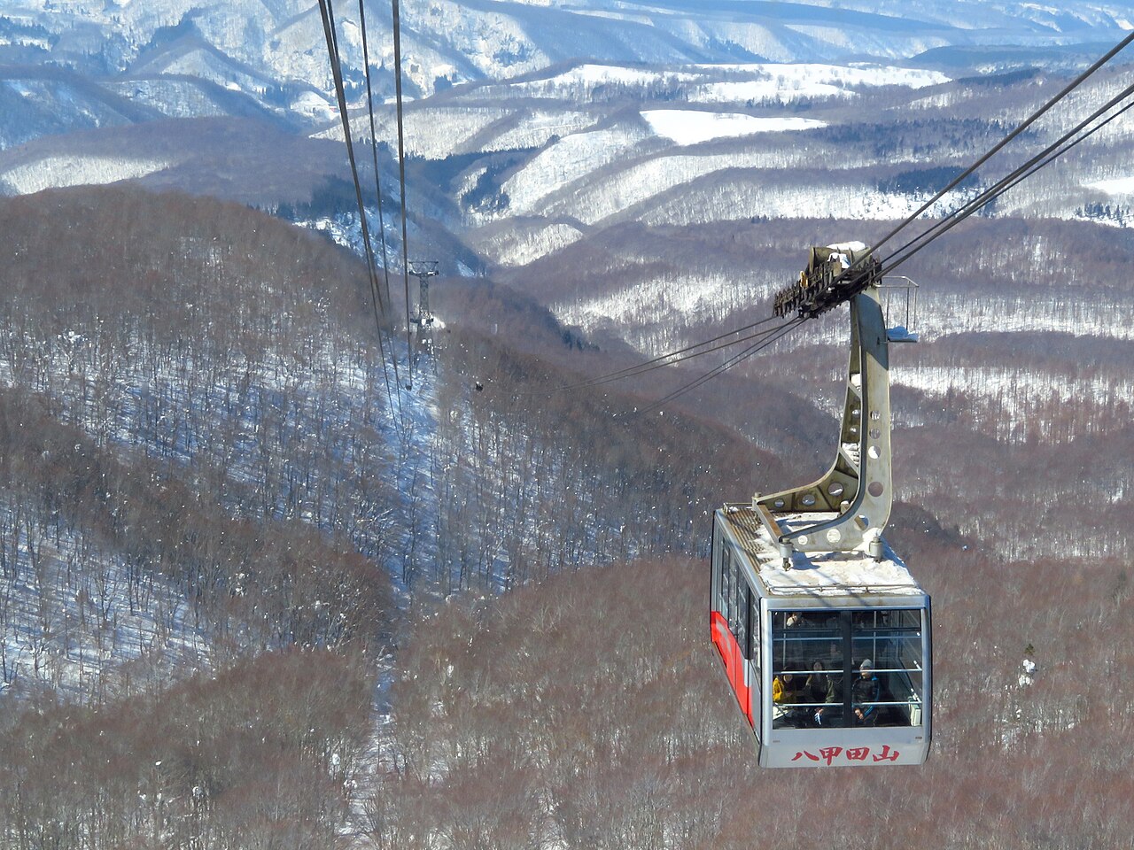 雪山の上を行く八甲田ロープウェーのゴンドラ。車体に「八甲田山」の文字