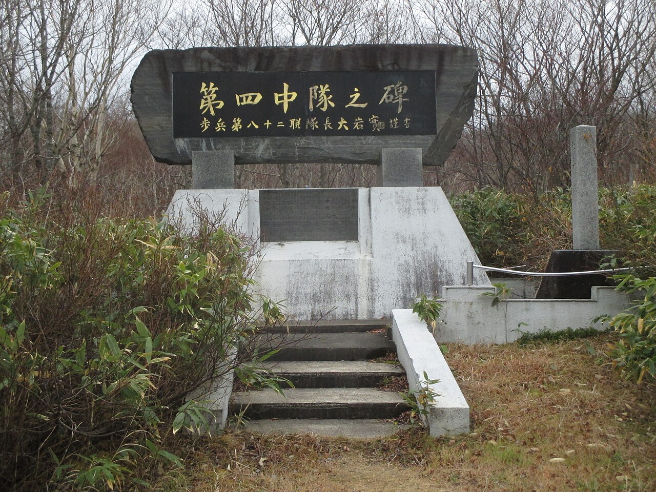 石段の上に立つ第四中隊之碑。八甲田山雪中行軍遭難の碑で、まわりを笹や低木が囲む