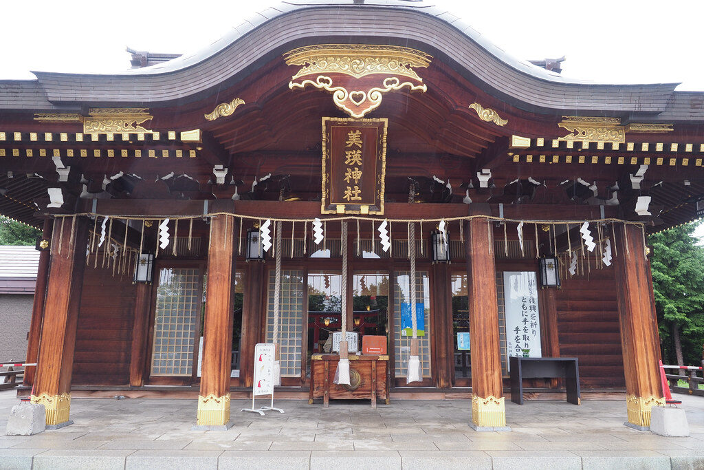 美瑛神社の社殿正面、屋根中央に輝く金色のハート文様と「美瑛神社」の扁額