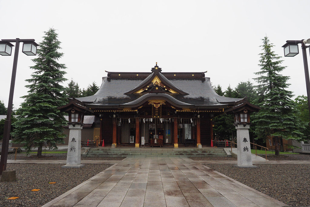 「奉納」と刻まれた石柱越しに望む美瑛神社の社殿と参道