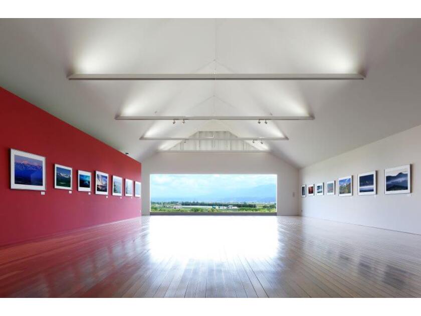 ギャラリー「神々の遊ぶ庭」の展示室と正面の窓から見える十勝岳の景色