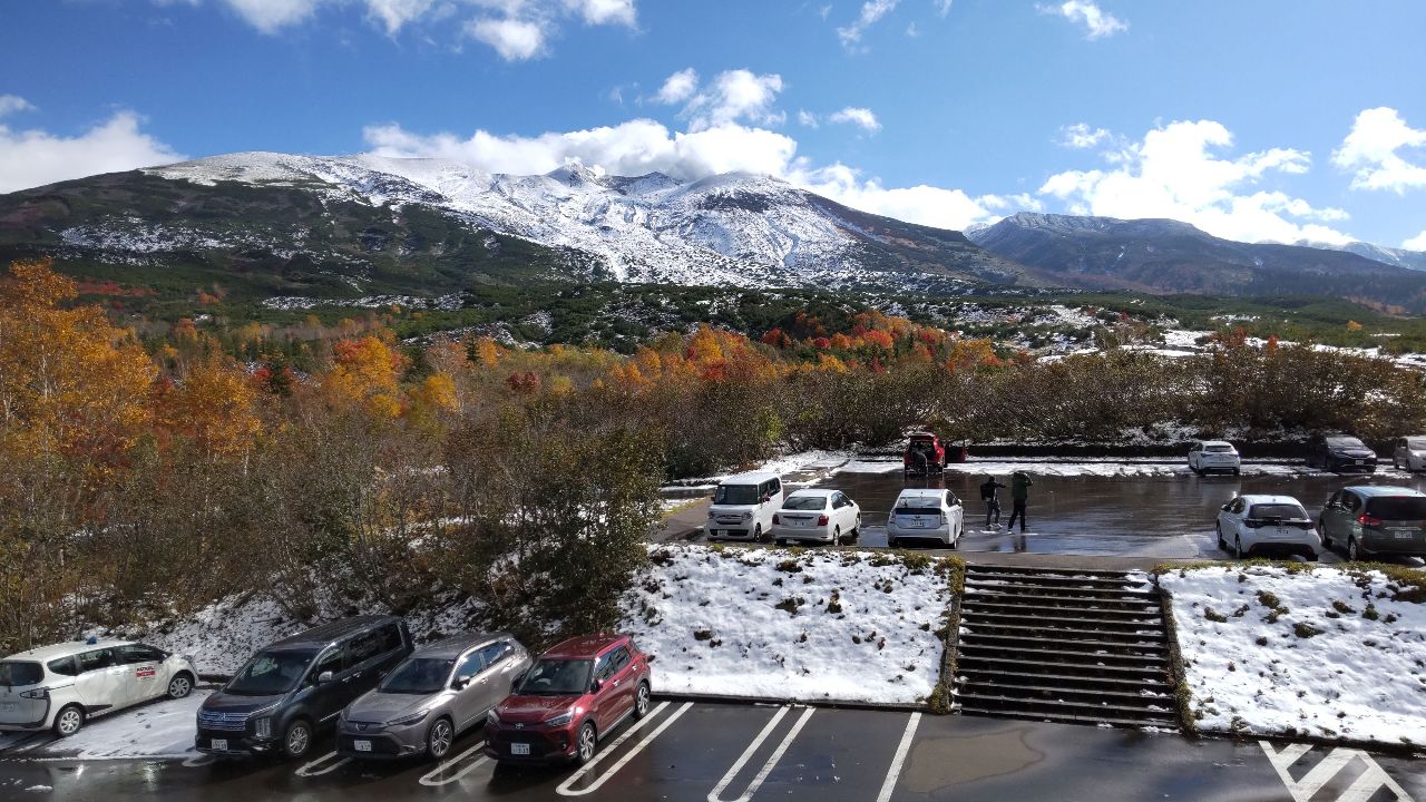 初雪の望岳台駐車場と紅葉、雪化粧した十勝岳連峰