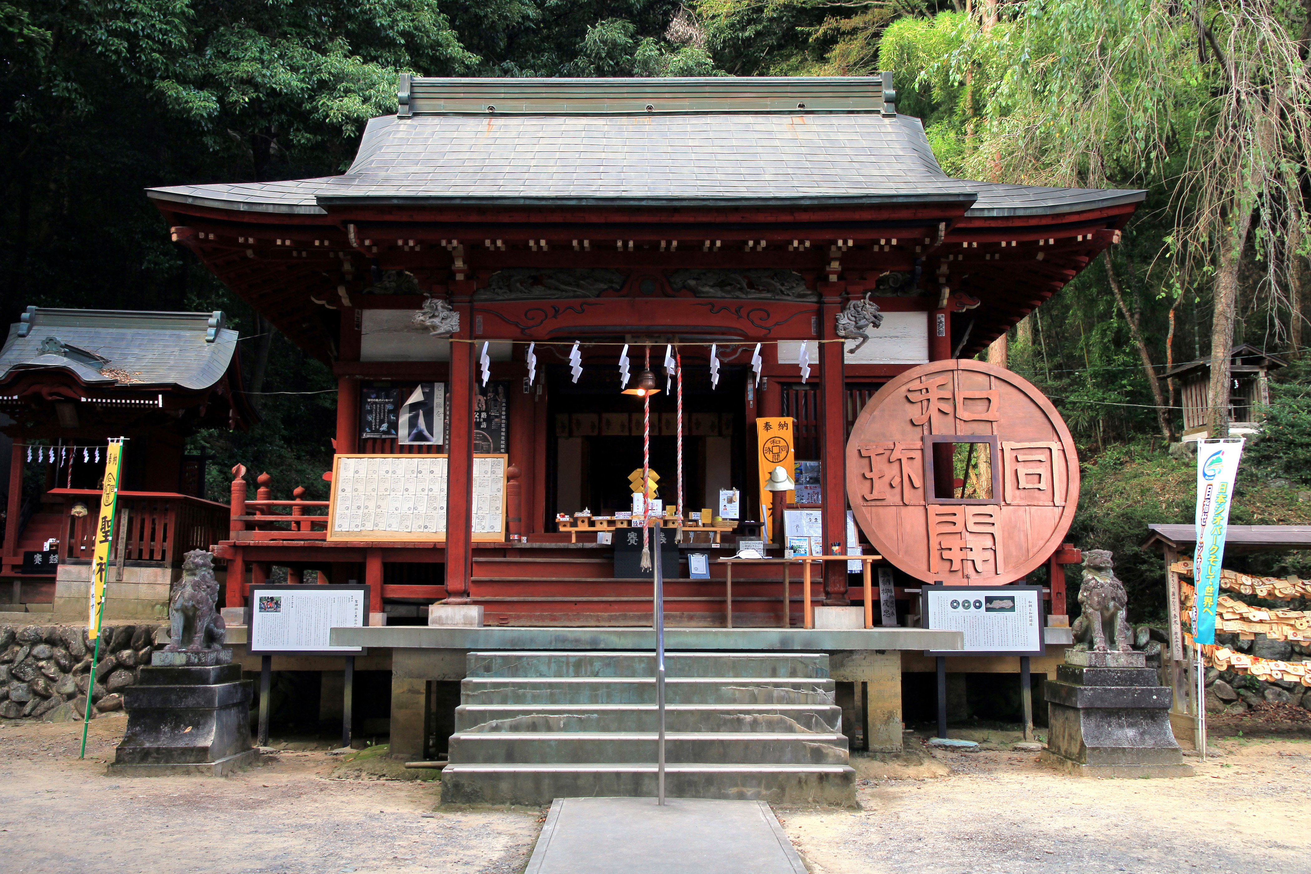 聖神社の拝殿正面と、境内に置かれた巨大な和同開珎のモニュメント