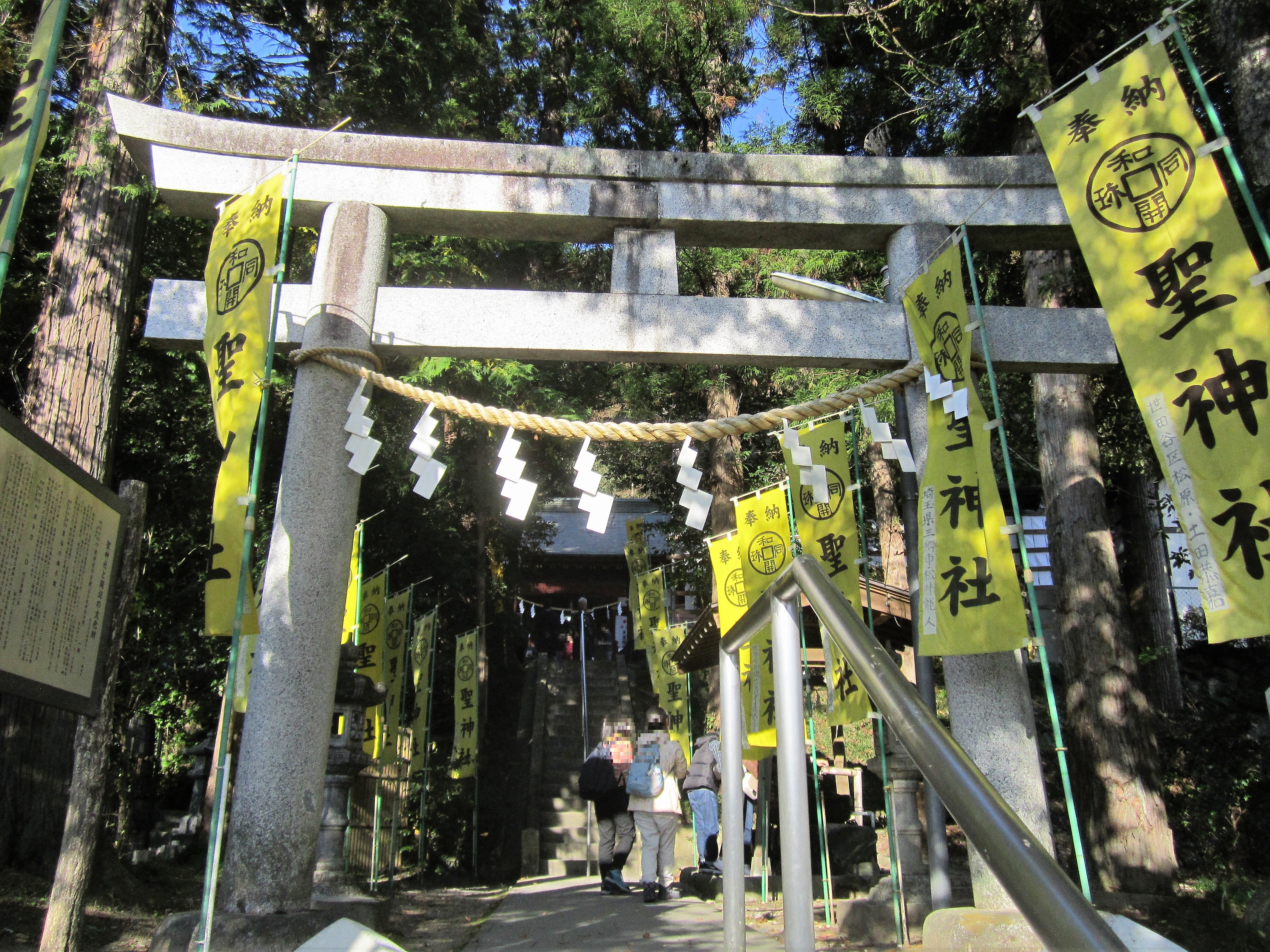 聖神社の鳥居と、聖神社と書かれた奉納のぼり旗が並ぶ参道