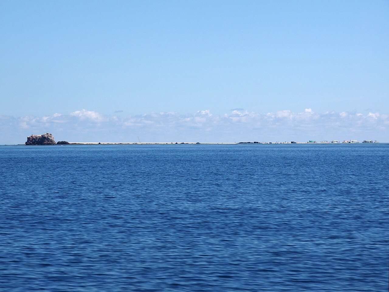幻の島に到着したツアー船と、島で過ごす観光客たち