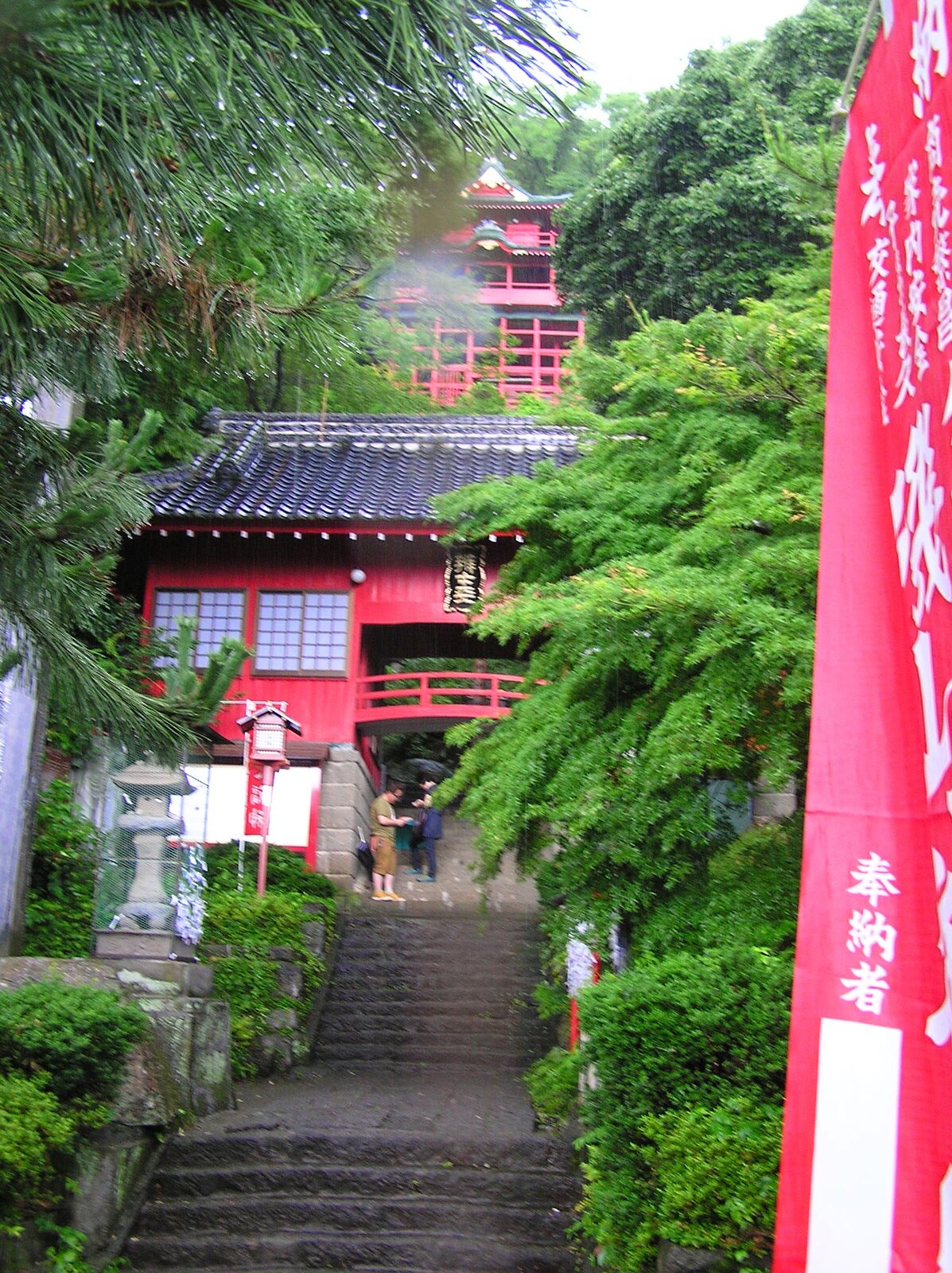 雨の日の磯山弁財天、緑に包まれた懸造りの社殿と奉納幟