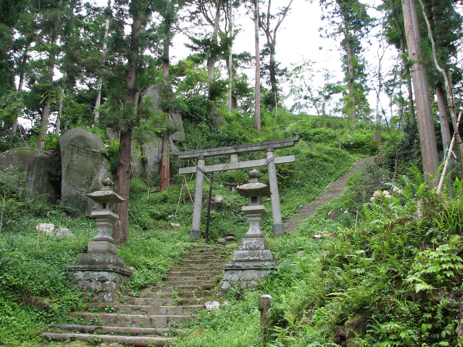 参道の鳥居と石灯籠、周囲に点在する巨石（磐座）