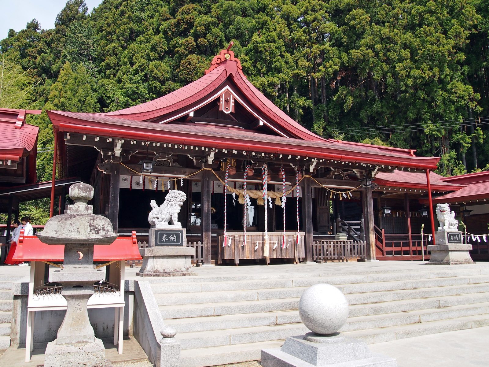 金蛇水神社の朱塗りの拝殿と一対の狛犬