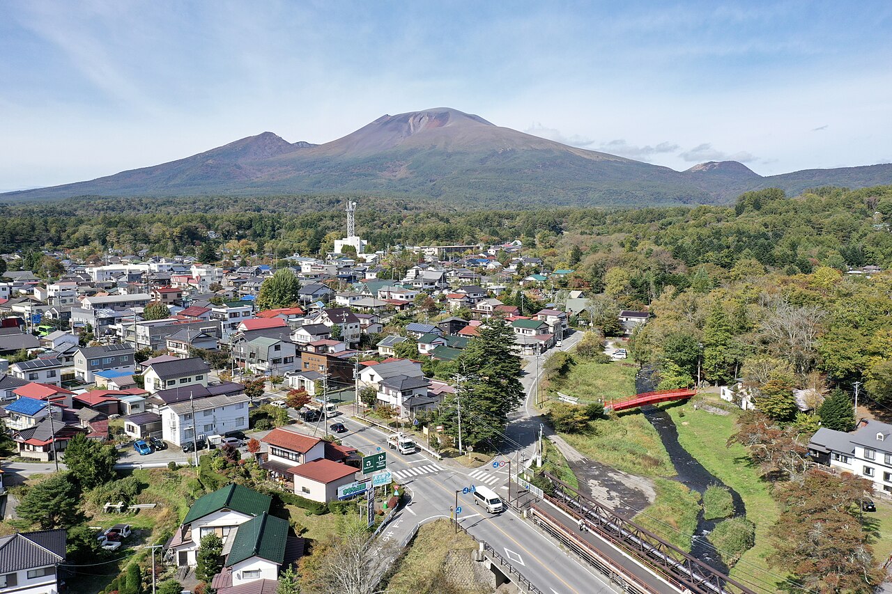 中軽井沢の街並みと、その奥にそびえる浅間山を俯瞰した眺め
