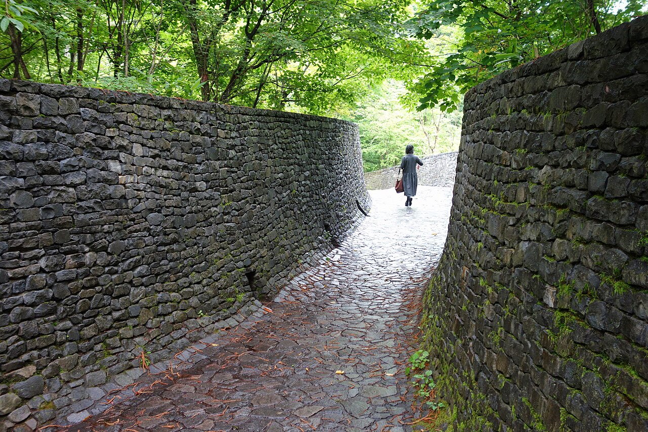 雨に濡れた石畳の通路と両側に湾曲した石積みの壁