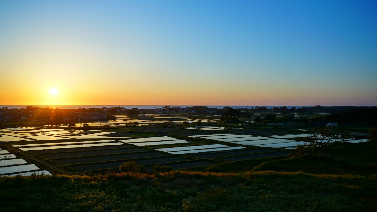 象潟の水田に沈む夕日と水鏡の風景