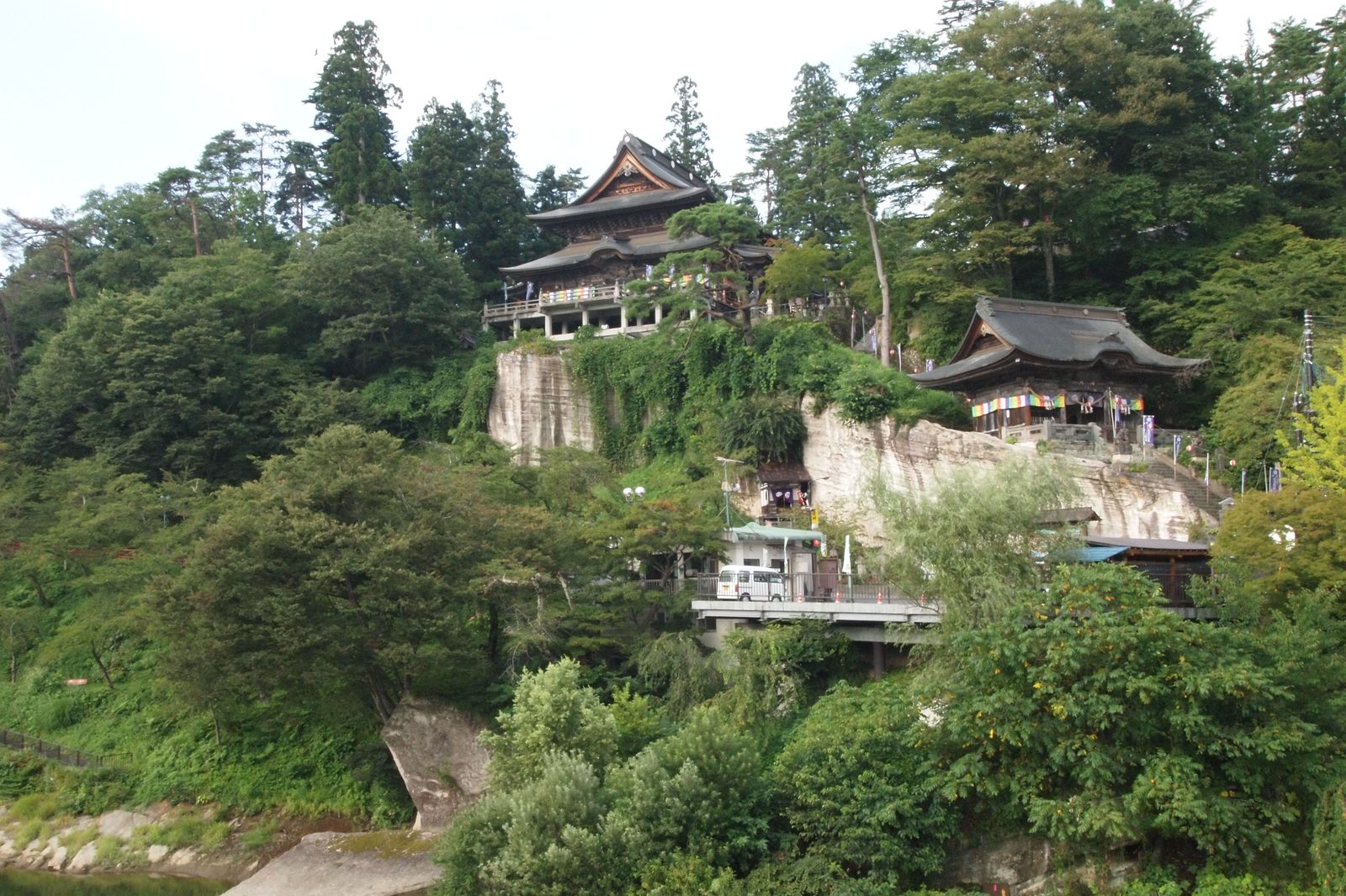 断崖の上に建つ圓藏寺の本堂と奥之院、夏の緑に包まれる境内