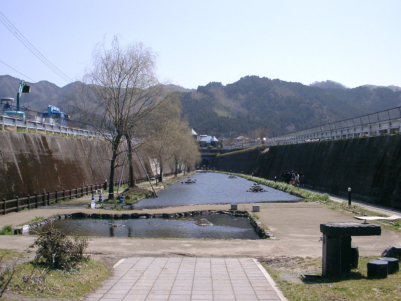高森湧水トンネル公園の水路と遊歩道、背後に広がる山並み