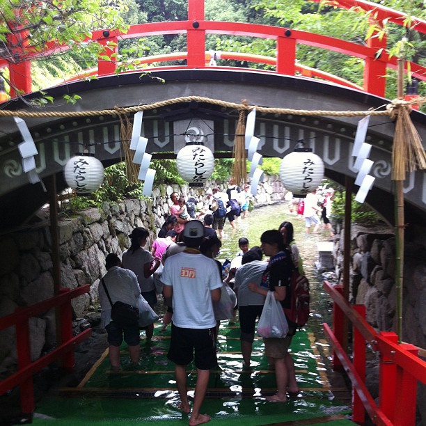 下鴨神社みたらし祭の御手洗池に足を浸す参拝者と「みたらし祭」の提灯