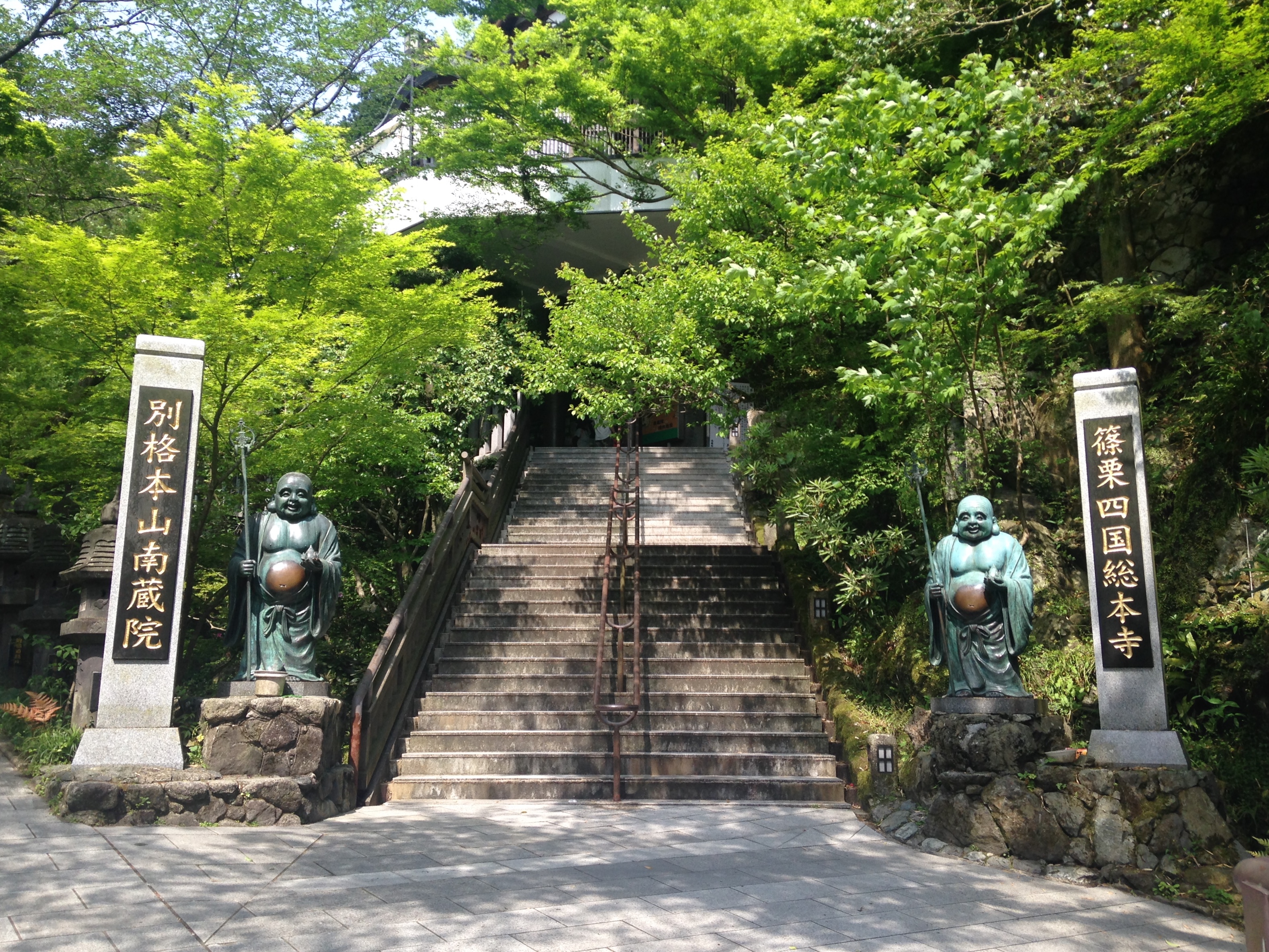南蔵院の山門と七福神の像、緑に包まれた参道の階段