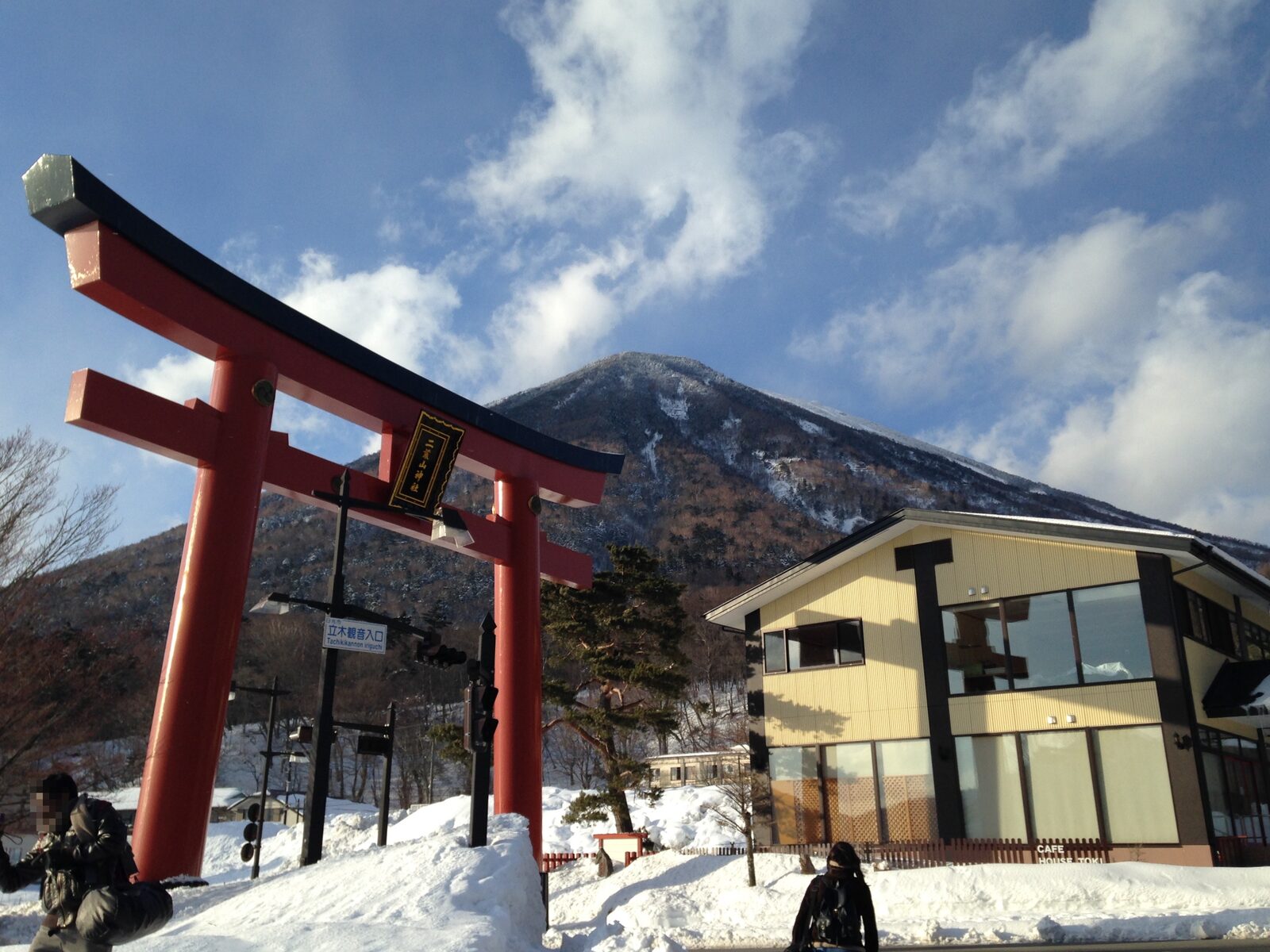 日光二荒山神社中宮祠の参道に立つ朱塗りの鳥居と、雪をいただく男体山