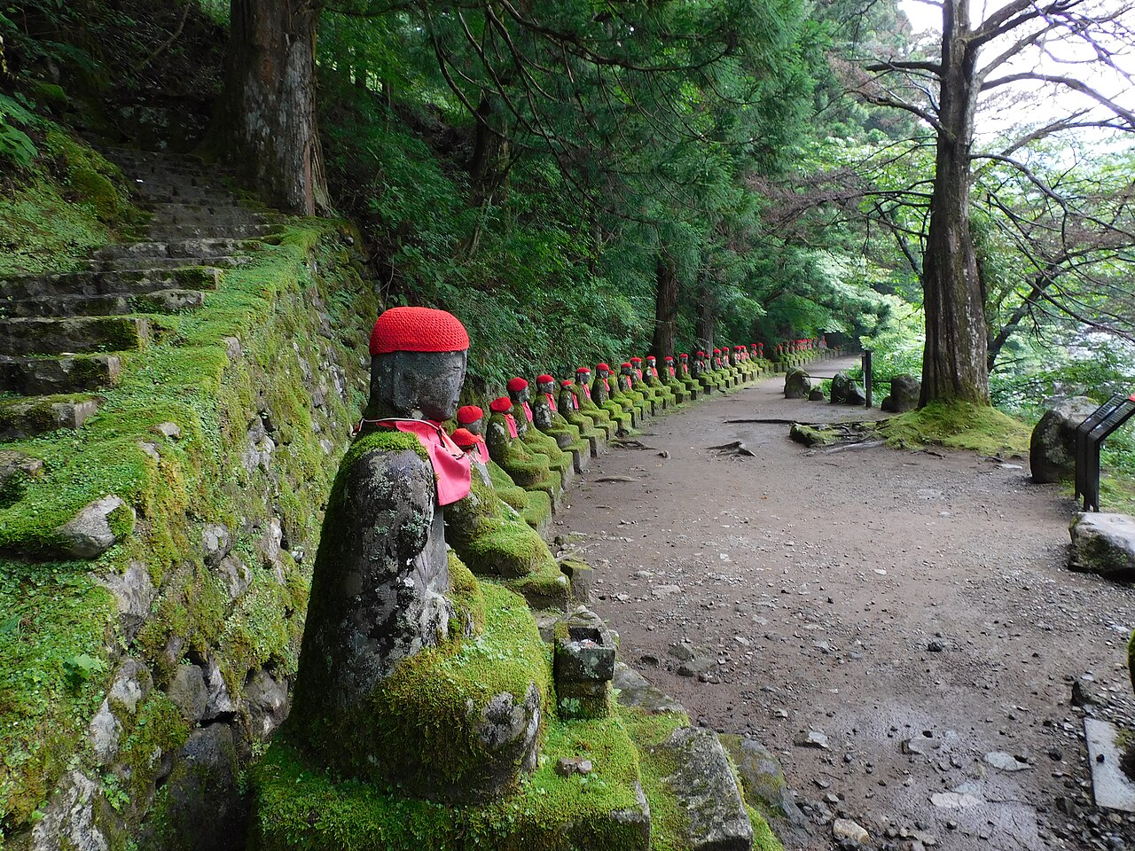 憾満ヶ淵の化け地蔵。赤い帽子と前掛けをまとった石地蔵が苔むした参道沿いに並ぶ