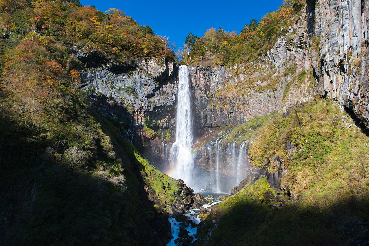 華厳滝の全景。落差97mの滝と紅葉、滝壺に架かる虹