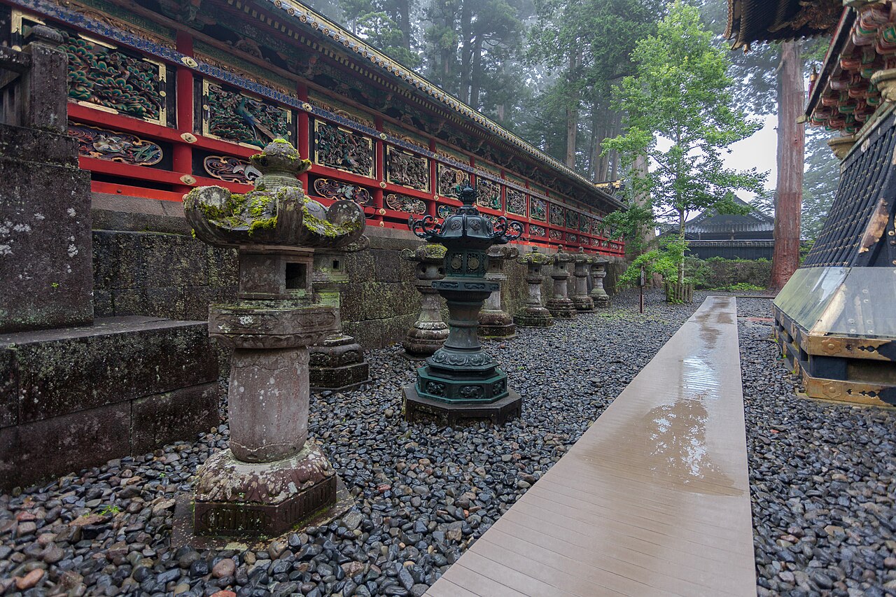 雨に濡れた日光東照宮の境内に並ぶ石灯籠と極彩色の透塀