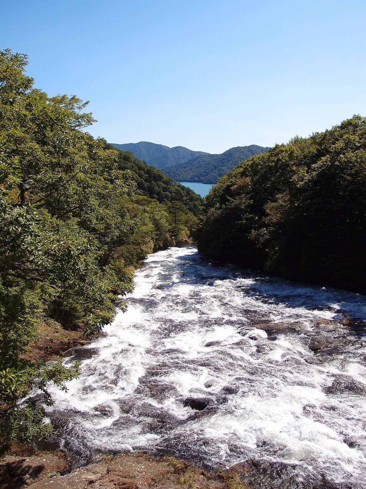 竜頭滝の上流から中禅寺湖を望む。白く砕ける瀬の先に湖面が光る