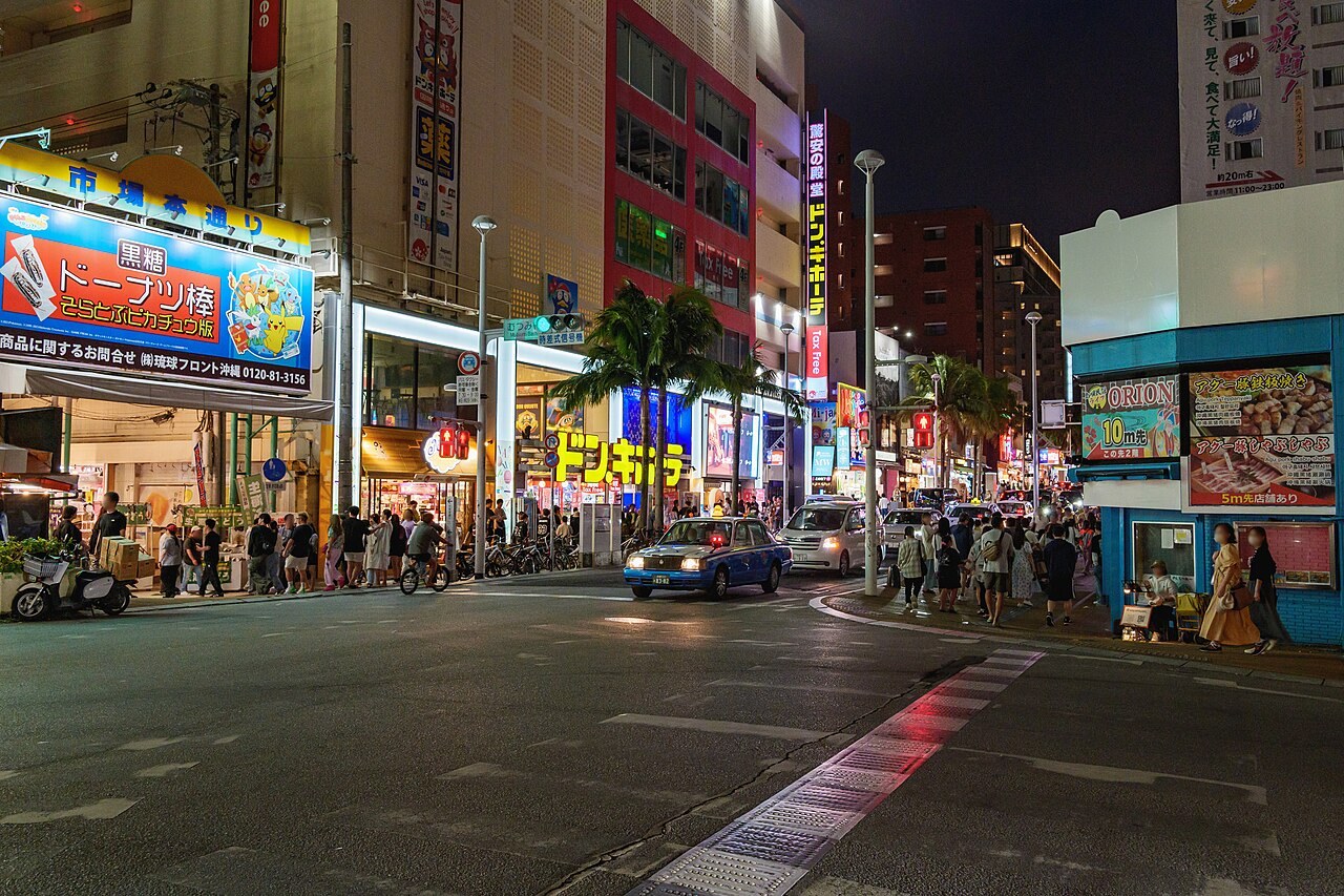 夜の国際通り。市場本通りのアーケード入口とネオン、青いタクシー