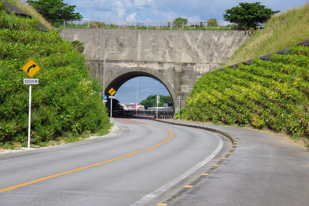 ニライカナイ橋のトンネルへ続くカーブした道路と県道86号の標識