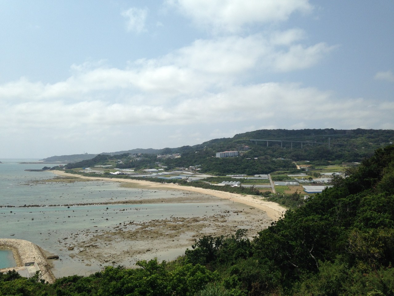 知念岬公園から望む南側の海岸線と、遠く丘の中腹に見えるニライカナイ橋の高架
