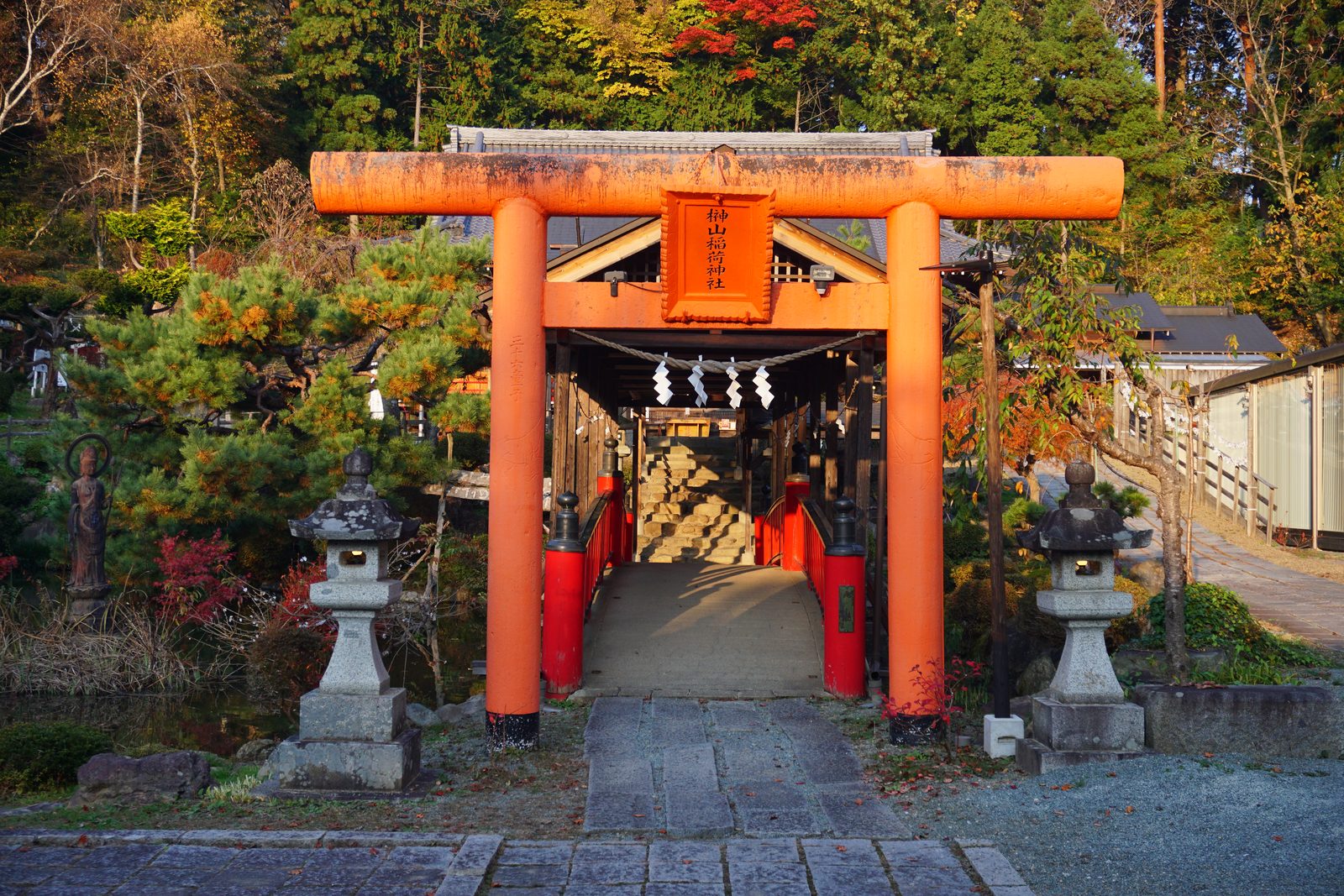 榊山稲荷神社(もりおかかいうん神社)の朱塗りの大鳥居と心字の池に架かる赤い橋、紅葉の境内