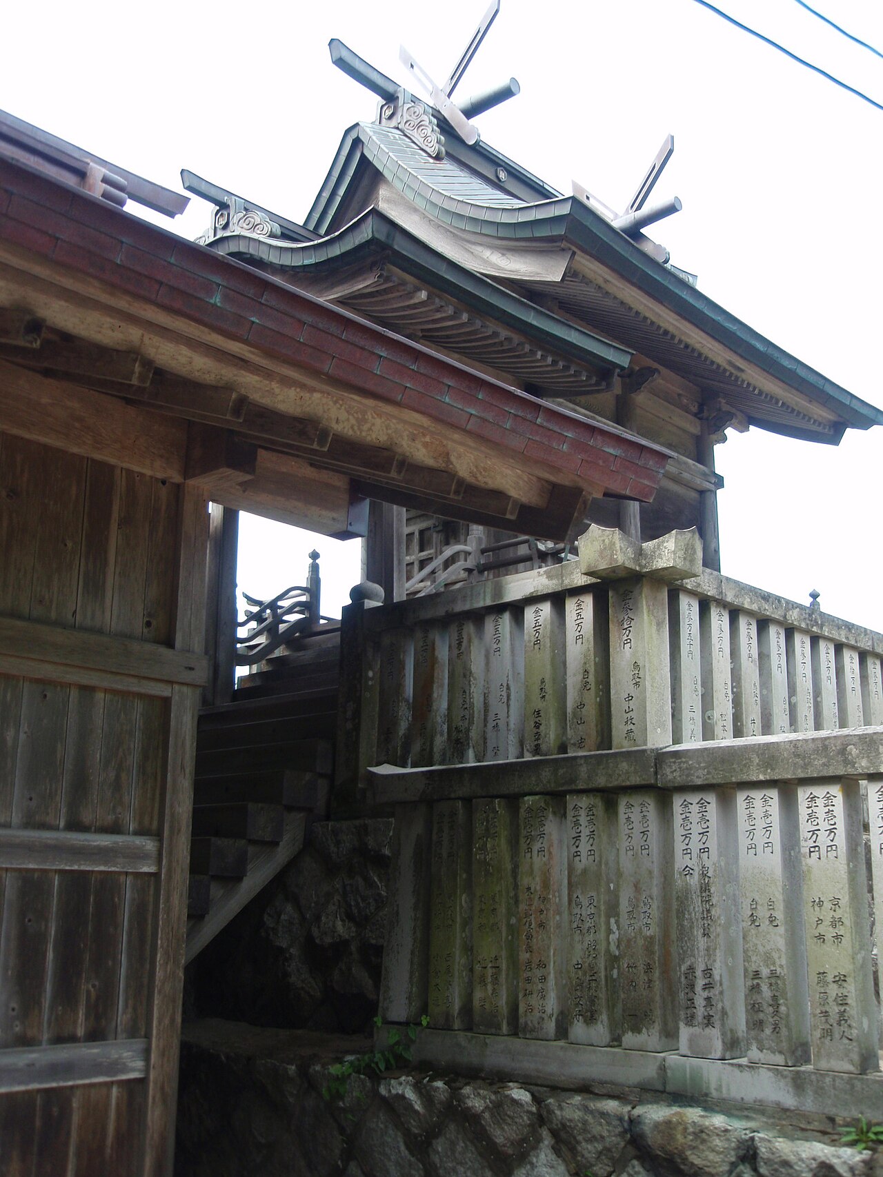 白兎神社の社殿を見上げる、木造の門と奉納された玉垣