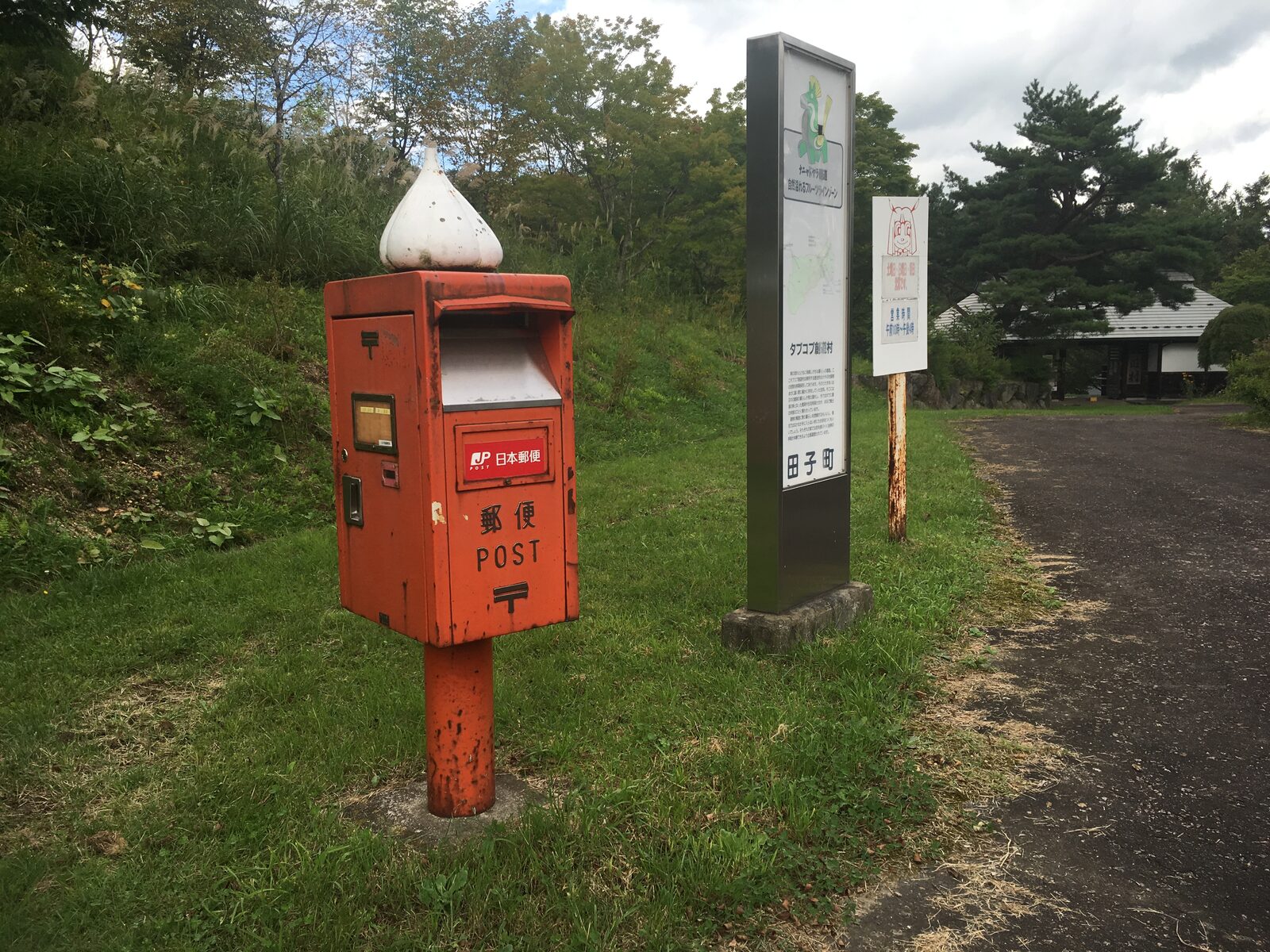 青森県田子町の集落に残る、にんにくの張り紙が下がる古民家と郵便ポスト