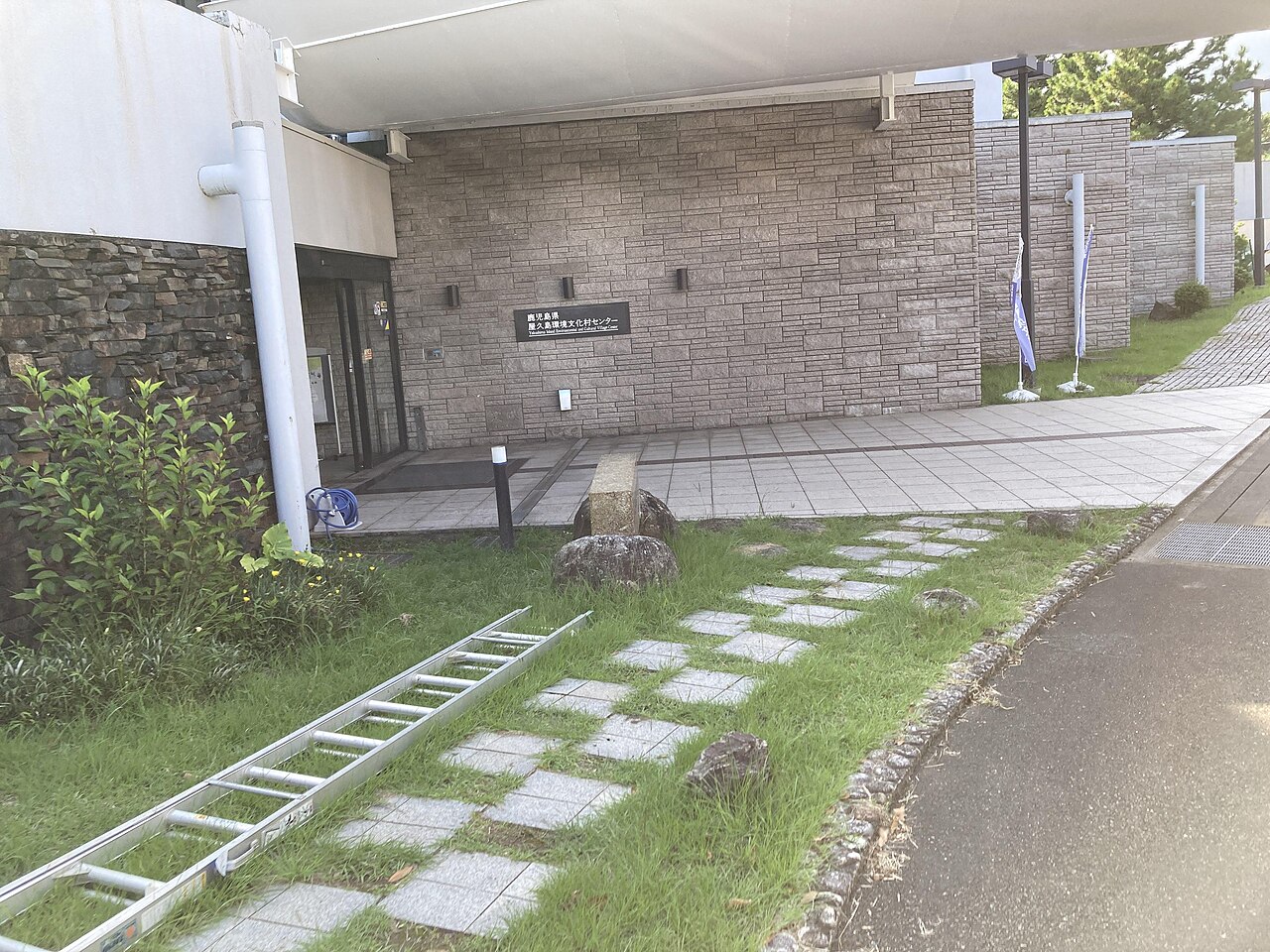 石張りの壁の屋久島環境文化村センター館名サインとエントランス、幟旗