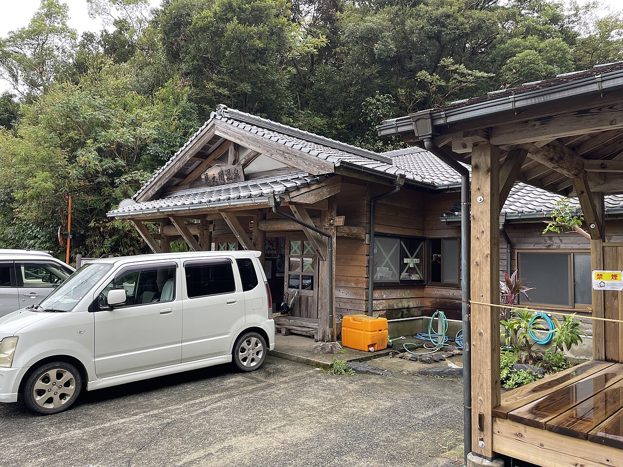 斜めから見た尾之間温泉の浴場と右手の東屋、背後は照葉樹の斜面