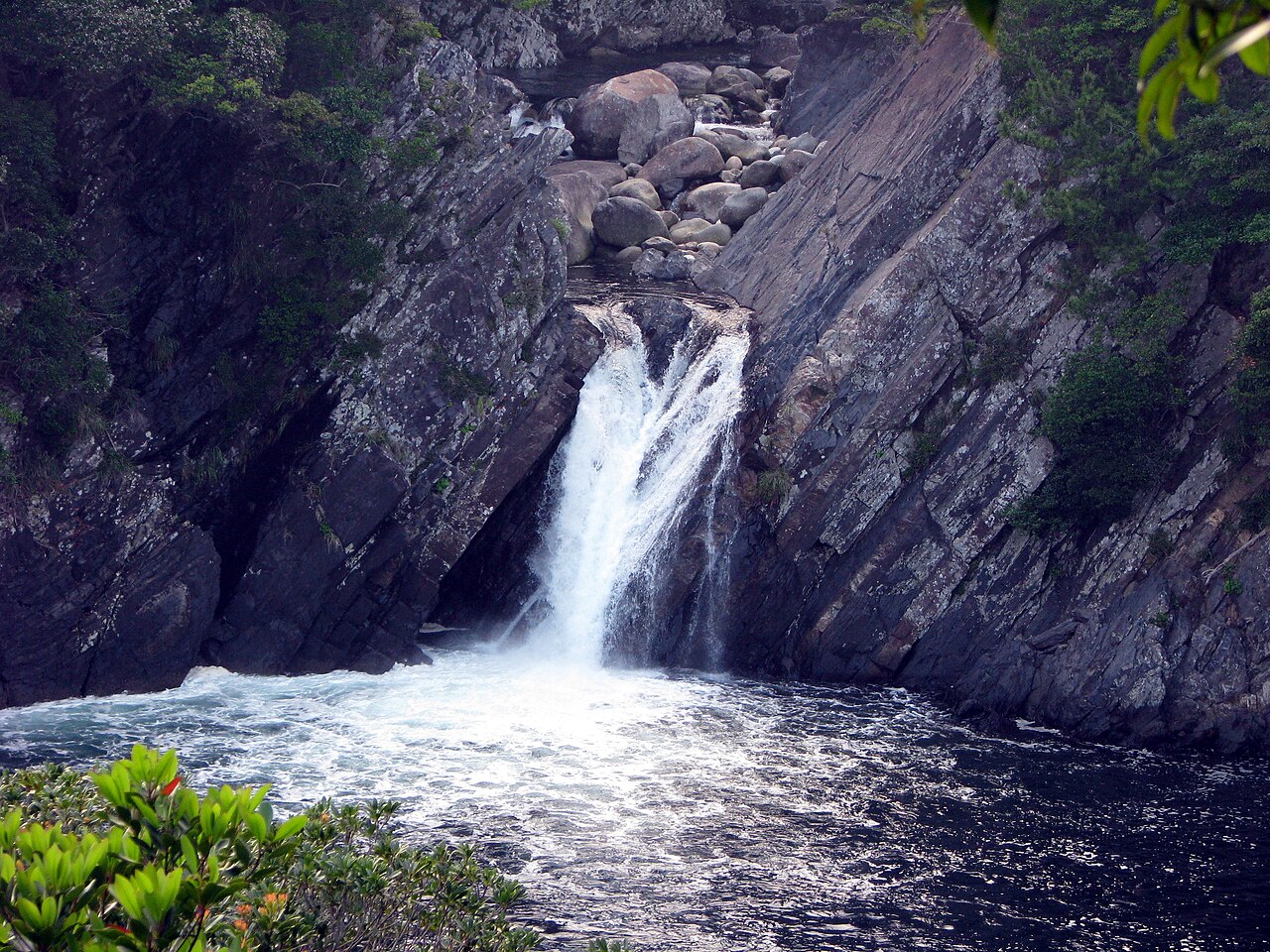 暗い海のたまりへ落ちるトローキの滝