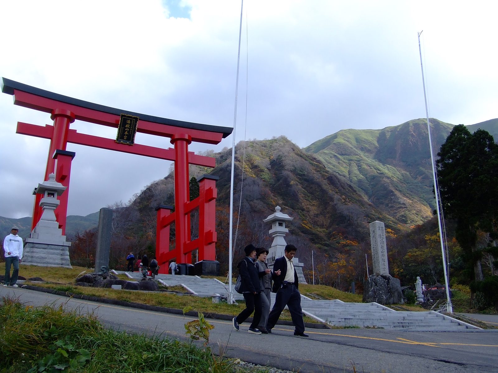 大鳥居の前を歩く参拝者と湯殿山の山並み