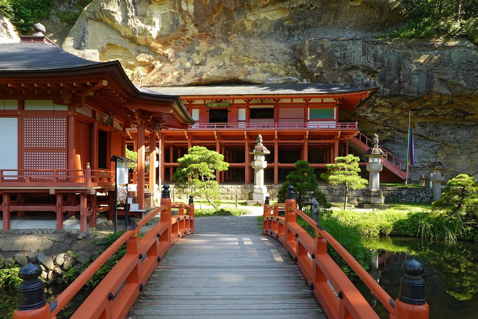 蝦蟆ヶ池に架かる朱色の橋と達谷窟毘沙門堂の本堂