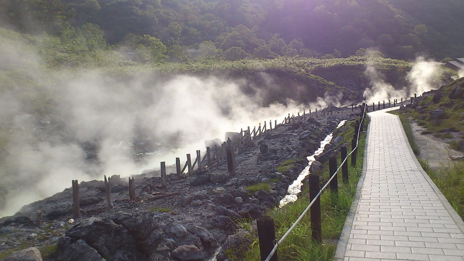 湯の花が採取される源泉沿いの遊歩道と立ち上る湯けむり