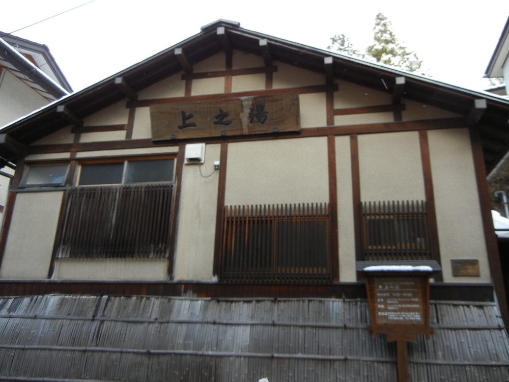 「上之湯」の看板を掲げた木造の共同浴場