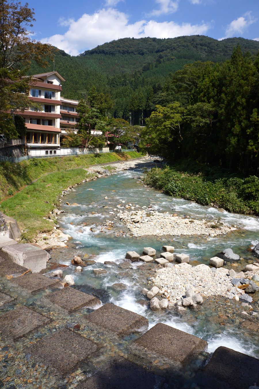 青く澄んだ四万川の流れと、川沿いに立つ宿