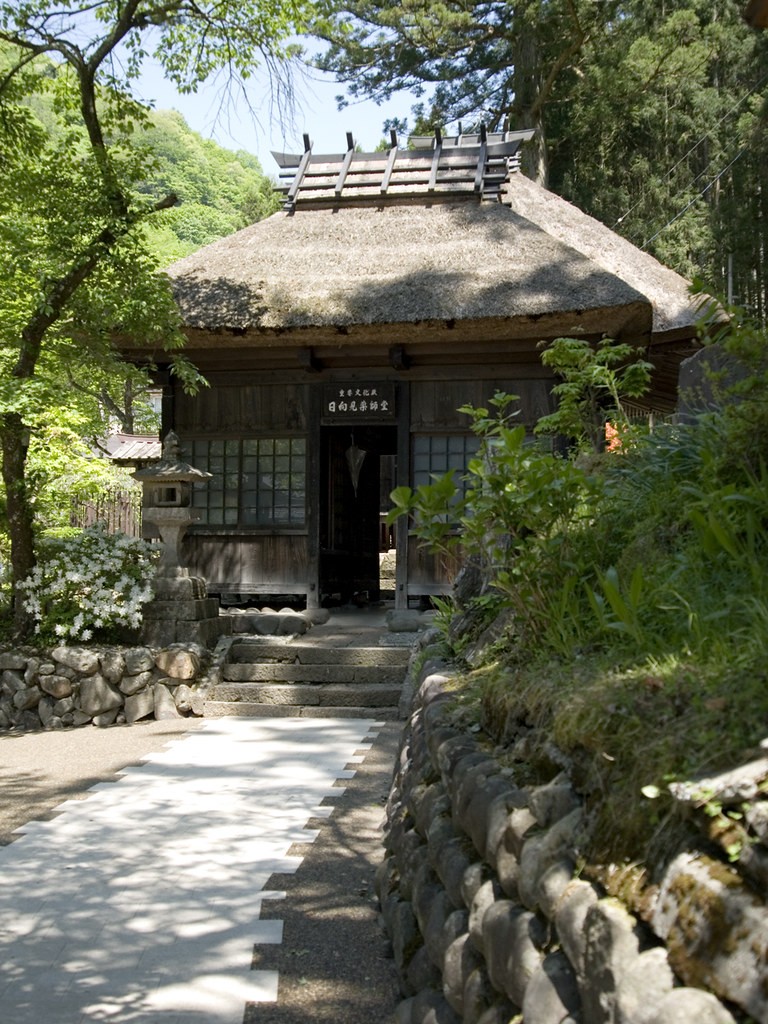新緑に囲まれた茅葺屋根の日向見薬師堂と、堂へ続く石段